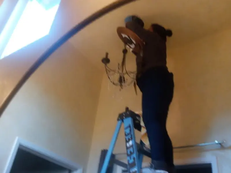 Electrician installing a chandelier in a Sanford residence